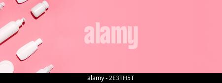 Banner with white cosmetic bottles mockup on pink background. Tubes, dispensers and jars. Branding identity concept. Flat lay with copy space Stock Photo