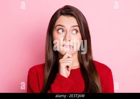 Portrait photo of pretty guilty female student biting lip touching chin thinking about solution of problem isolated on pink color background Stock Photo