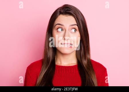 Portrait photo of troubled young girl with guilty face biting lip looking at side isolated on pink color background Stock Photo