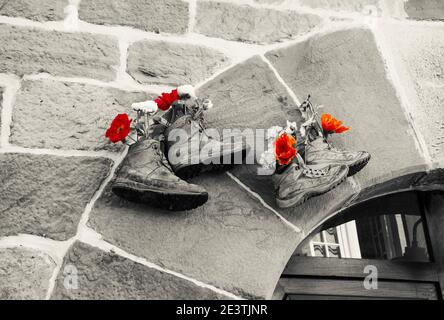 Old hiking shoes using as flower pot hanging stone wall house. Retro toned black white red vintage background. Lifestyle, natural leaving, travel, sus Stock Photo