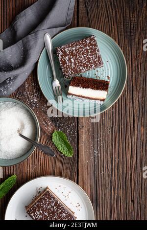 Delicious homemade dessert, fudgy coconut brownies topped with chocolate ganache glaze on rustic wooden background Stock Photo