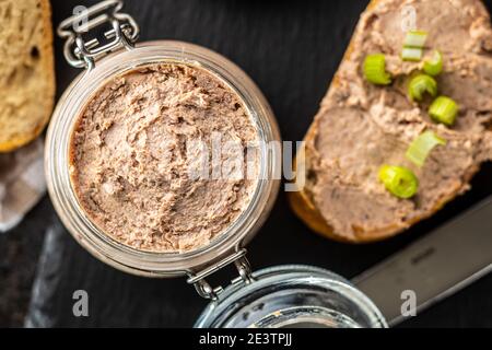 Liver pate in jar on black table. Top view. Stock Photo