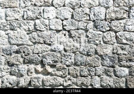Fragment of a fortified wall made of stones and cemented with cement mortar. Black and white. Stock Photo