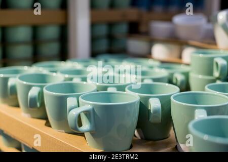 Background of empty ceramic cups.White and blue cups on the shelves in the store.concept of coffee addiction and crockery products.Stack of clean mint Stock Photo