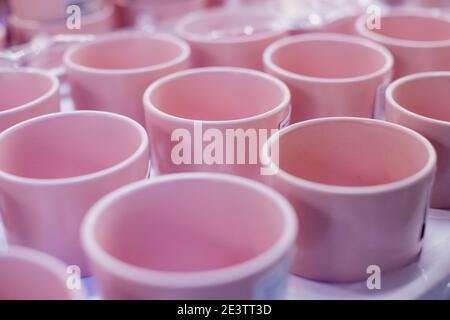 Background of empty ceramic cups.White and blue cups on the shelves in the store.concept of coffee addiction and crockery products.rows of clean pink Stock Photo