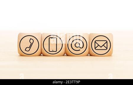 Contact us icons in wooden blocks on wooden desk. Copy space. White background Stock Photo
