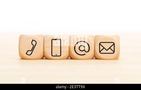 Contact us icons in wooden blocks on wooden desk. Copy space. White background Stock Photo
