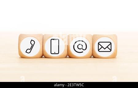 Contact us icons in wooden blocks on wooden desk. Copy space. White background Stock Photo