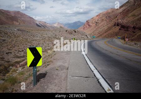 Sharp turn warning sign on mountain road. Highway road in Andes Mountains. Mendoza province, Argentina Stock Photo
