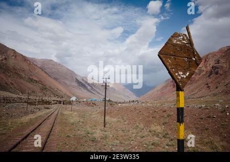 Damaged railway road sign near old abandoned railroad in desert in Andes Mountains near Puente del Inca village, Mendoza province, Argentina Stock Photo