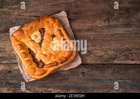 Homemade apple pie on kraft paper on a brown wooden background. Stock Photo