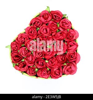 Photo of a Heart shaped paper and card Valentine's day gift box of chocolates with red paper roses and green leaves from above white background Stock Photo