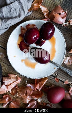 Dyed Easter eggs painted with natural dye onion on rustic wooden background. Process of dyeing eggs with natural paints for Easter. Natural ecological Stock Photo