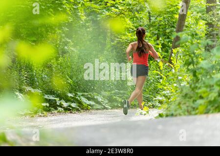 Woman runner running in the green woods summer active sport lifestyle Stock Photo