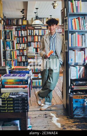 smiling young man holding book in bookshop Stock Photo