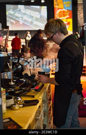 Barista pouring steamed milk into coffee cup making latte art. Stock Photo