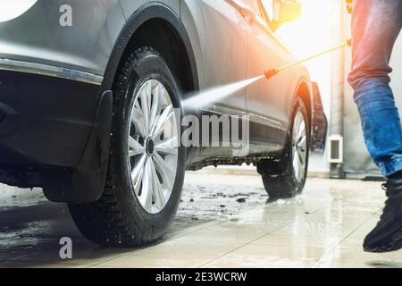 Car wash. Man washes car with water from high pressure washer. Stock Photo