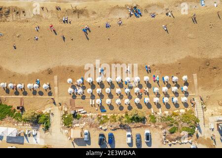 Tropical sandy beach with white umbrellas, aerial top view from drone. Stock Photo