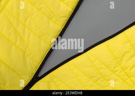 Stretched zipper lock of yellow jacket on gray background. Colors of the Year 2021 Pantone Illuminating and Ultimate gray Stock Photo
