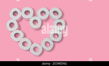 Heart made from rolls of toilet paper on a pink background. Valentines day during pandemic concept. Flat lay. Copy space Stock Photo
