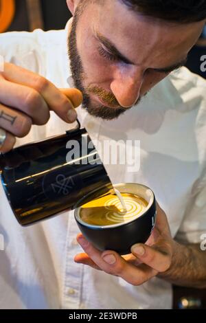 Yuri Marschall latte art champion from Germany pouring steamed milk into coffee cup making latte art. Stock Photo