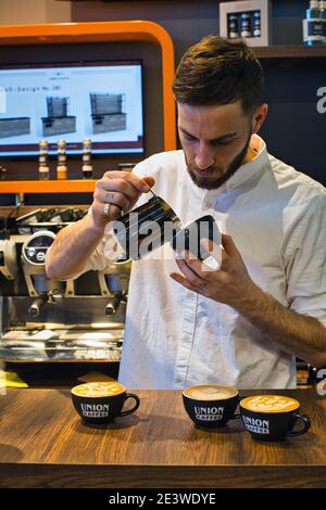 Yuri Marschall latte art champion from Germany pouring steamed milk into coffee cup making latte art. Stock Photo