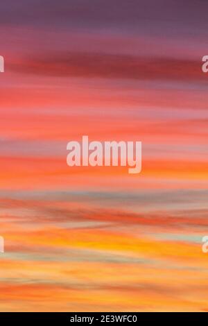 Dusk's setting sun creates clouds with stripes colored hot pink and orange sherbet. Stock Photo
