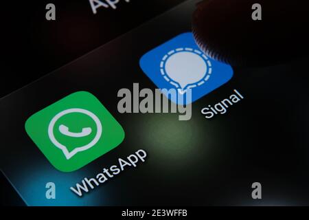 Signal and WhatsApp apps and blurred finger above them. The apps switching popularity in the United States due to secu Stock Photo
