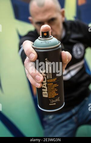 Street graffiti artist painting with a color spray can mural graffiti ...