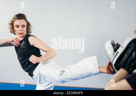 Personal training martial art of taekwondo. Female trainer holding taekwondo kick pad, athlete trainers kicks. Woman kicking strike shield, sparring t Stock Photo