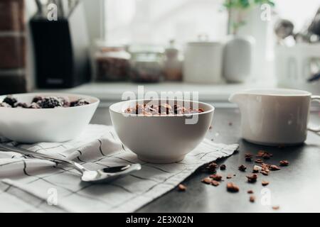 Frozen blackberries, granola, cream, towel on table. Blurred background Stock Photo