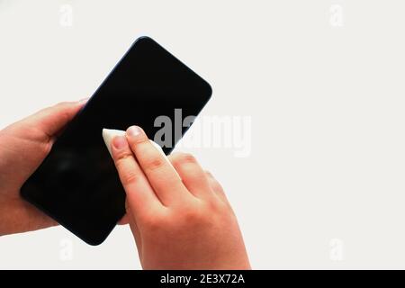 boys hands rubs modern smartphone with a disinfectant wipe. coronavirus protection. virus outbreak prevention. personal hygiene importance. Stock Photo