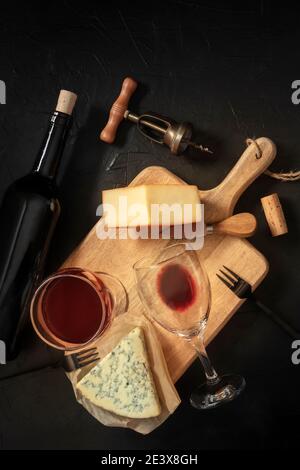 Wine and cheese tasting, shot from above on a black background, with a cork, vintage corkscrew, and a bottle Stock Photo