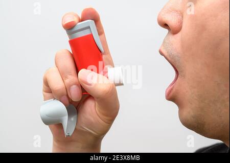 Asthmatic man suffers from asthma and is using inhaler. Stock Photo