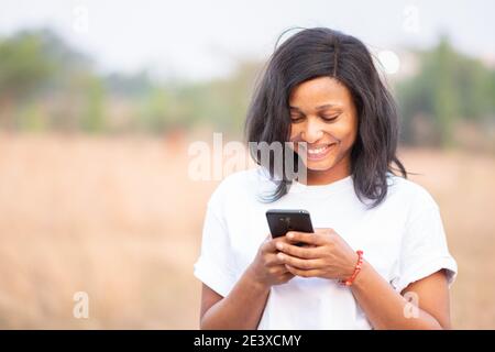 beautiful light skin african lady with freckles smiling while using her phone Stock Photo