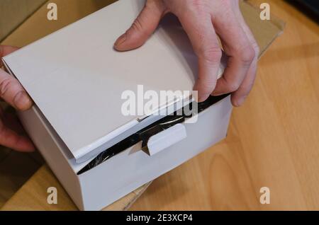 Delivery and checking online shopping concept. Man holds parcel in white rectangular cardboard box. Side view at an angle. Selective focus. Stock Photo