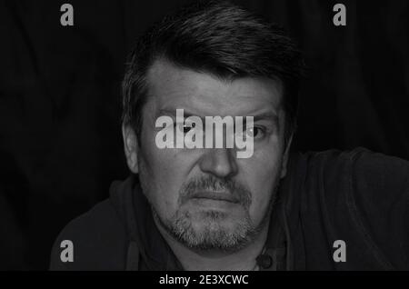 Monochrome portrait of a middle-aged man looking past the camera. Caucasian man with gray stubble. Stock Photo
