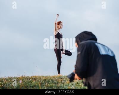 A slender woman is engaged in yoga in nature in the mountains in leggings and a T-shirt Stock Photo