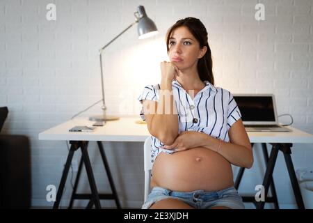 Tired pregnant woman working from home on computer Stock Photo