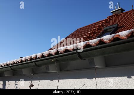 The snow on the roof melts and forms ice icicles. Stock Photo