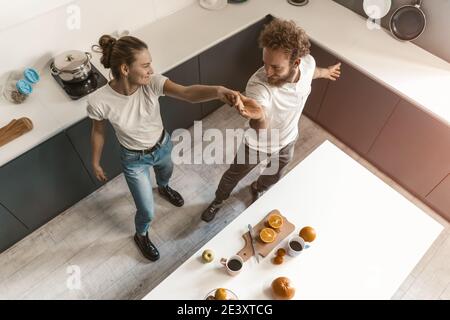 Top view. Young couple dancing in kitchen wearing casual clothes while cooking together at home in love having fun. Love, family, happiness concept Stock Photo