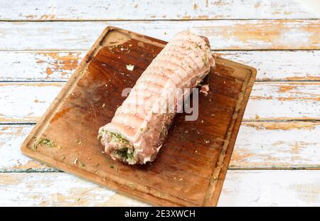 Preparation of a porchetta with a mixture of aromatic herbs placed on a piece of fresh pork belly open in the thickness Stock Photo