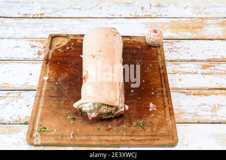 Preparation of a porchetta with a mixture of aromatic herbs placed on a piece of fresh pork belly open in the thickness Stock Photo