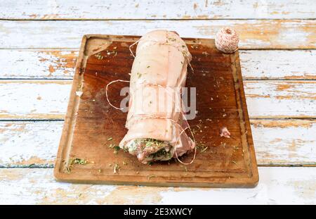Preparation of a porchetta with a mixture of aromatic herbs placed on a piece of fresh pork belly open in the thickness Stock Photo