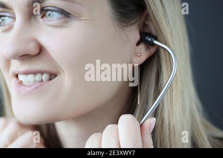 Doctor cardiologist inserting stethoscope into ears in clinic Stock Photo