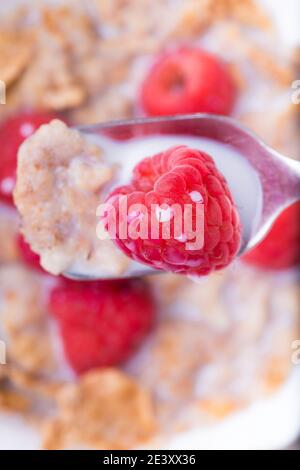 top view, close-up, a spoon with brown rice flakes, milk and fresh raspberries. Stock Photo