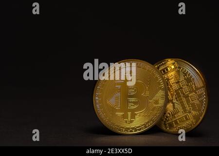 two golden shiny valuable bitcoin with front and back side with black detail view Stock Photo