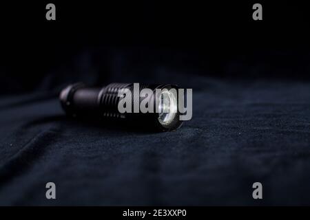 a tactical flashlight on black background shines Stock Photo