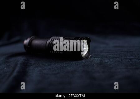 a tactical flashlight on black background shines Stock Photo