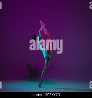 Motion. Young female athlete, rhythmic gymnastics artist dancing, training  isolated on purple studio background in neon light. Beautiful girl  practicing with equipment. Grace in performance Stock Photo - Alamy